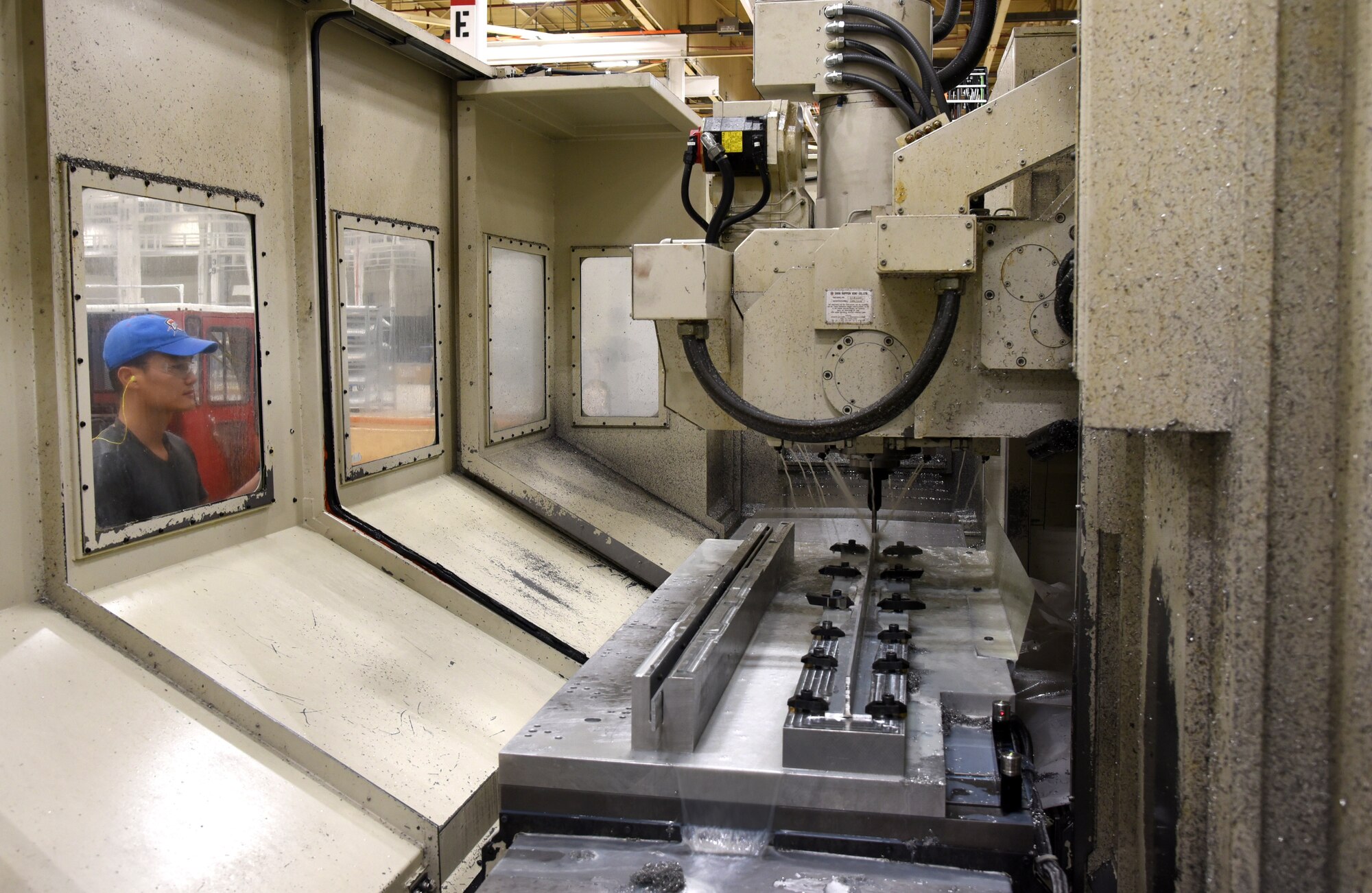 Truyen Ngo, with the 76th Commodities Maintenance Group’s Numerical Control Machine Shop, watches through the window of an SNK-80V CNC Milling Machine as specific cuts and joggles are formed on a keel beam for a KC-135 aircraft. (U.S. Air Force photos/Kelly White)