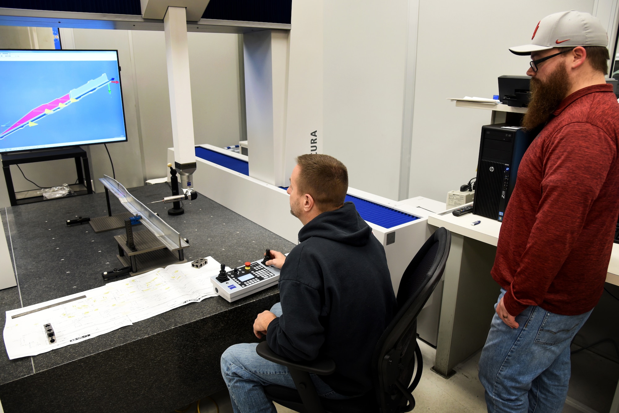 In the Precision Grind Shop, Ryan Danuser, right, and Ty Warden perform a quality verification of accurate dimensions of the keel beam before the part goes out to the customer. (U.S. Air Force photo/Kelly White)
