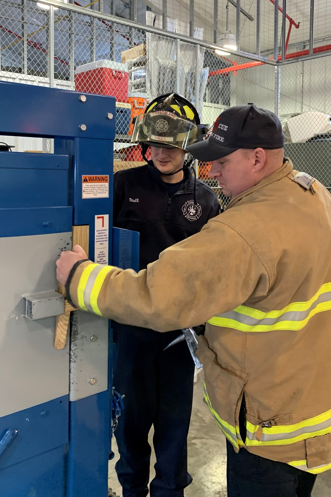 Bill Ralstin and Cory Paull, firefighters with the Grissom Fire Department, adjust the resistance on the forcible entry training door January 31, 2019 at the fire station garage. The department acquired the door in late 2008 to train first responders on breaking open doors more effectively. (U.S. Air Force photo by Staff Sgt. Courtney Dotson-Essett)