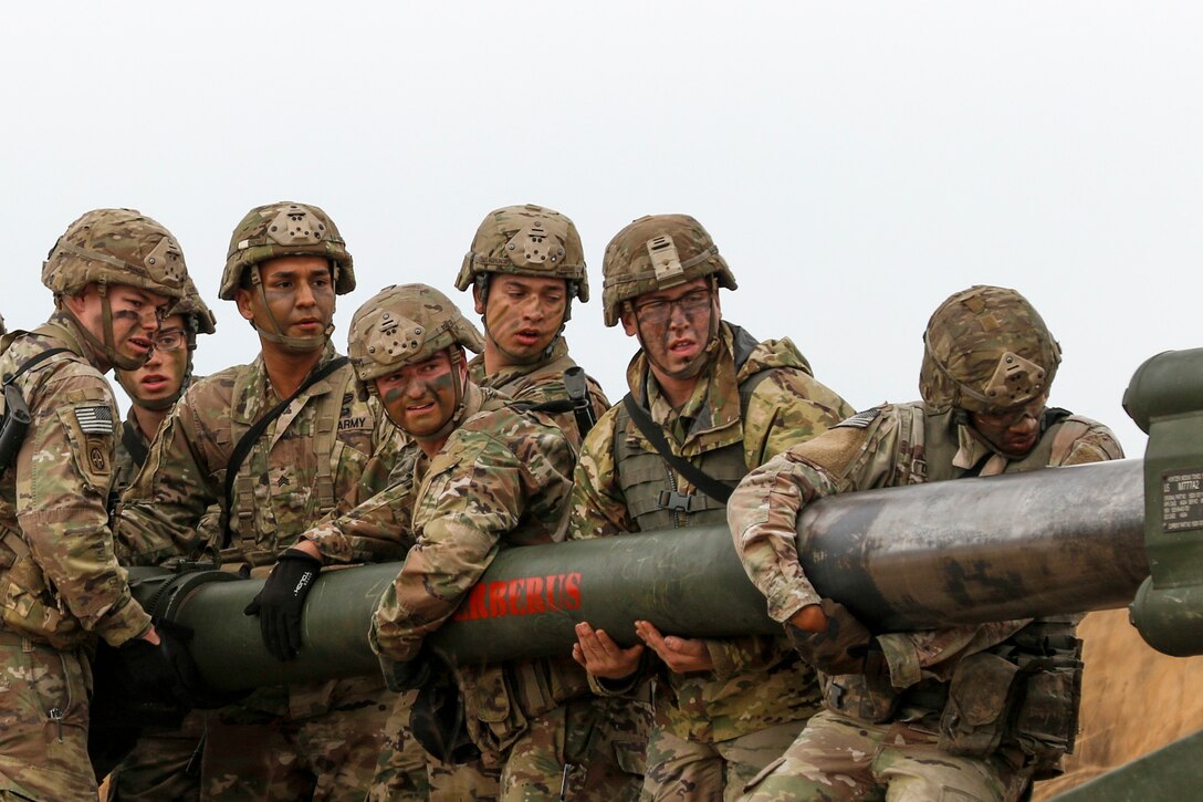 A group of soldiers moves the gun of a howitzer.