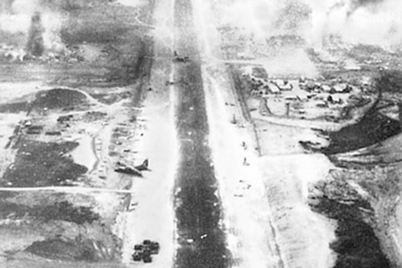 A distant photo of a foggy airfield and runway littered with debris and airplanes.