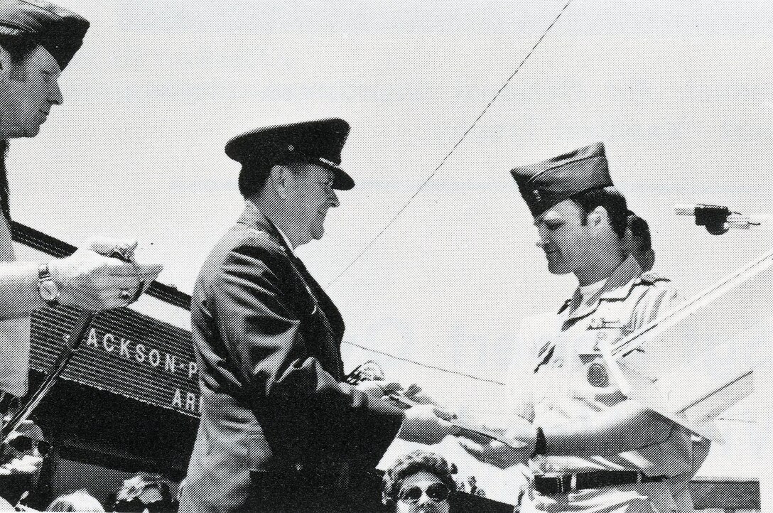 An airman in dress uniform accepts a saber from an Army National Guard officer.