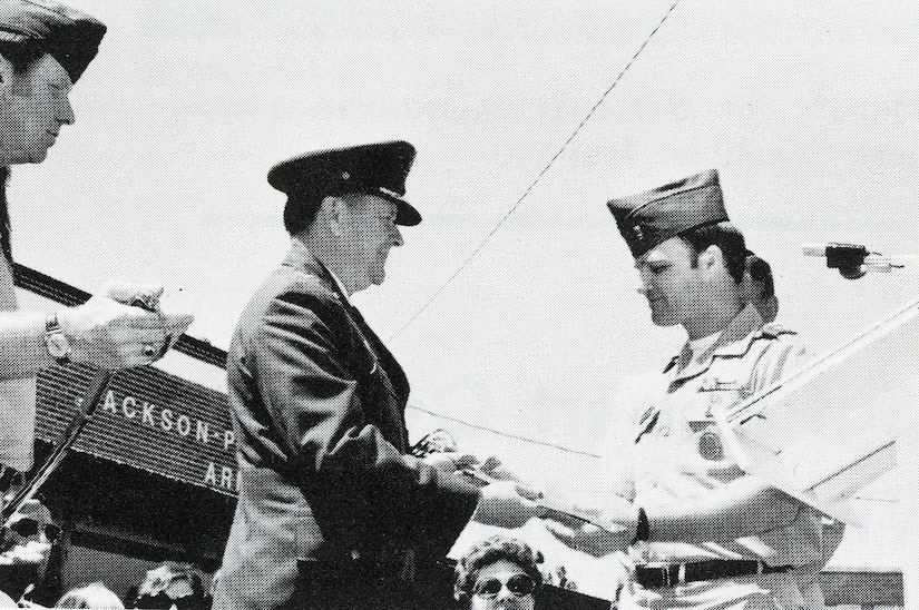 An airman in dress uniform accepts a saber from an Army National Guard officer.