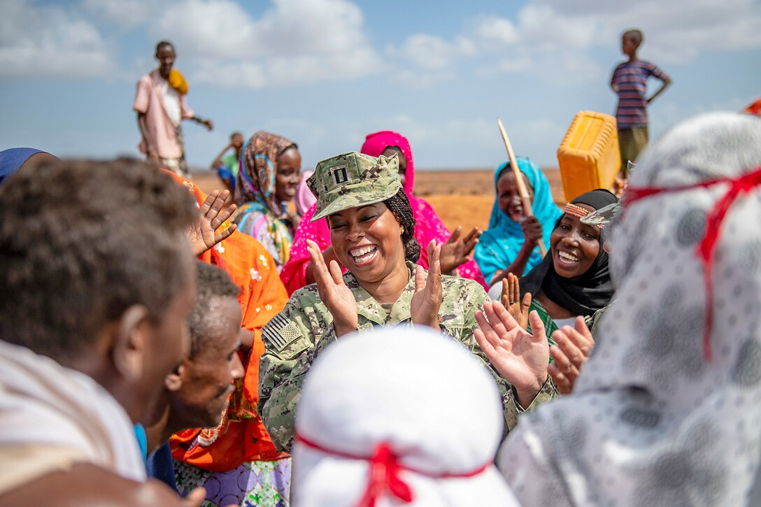 A sailor laughs and claps with Djibouti citizens.