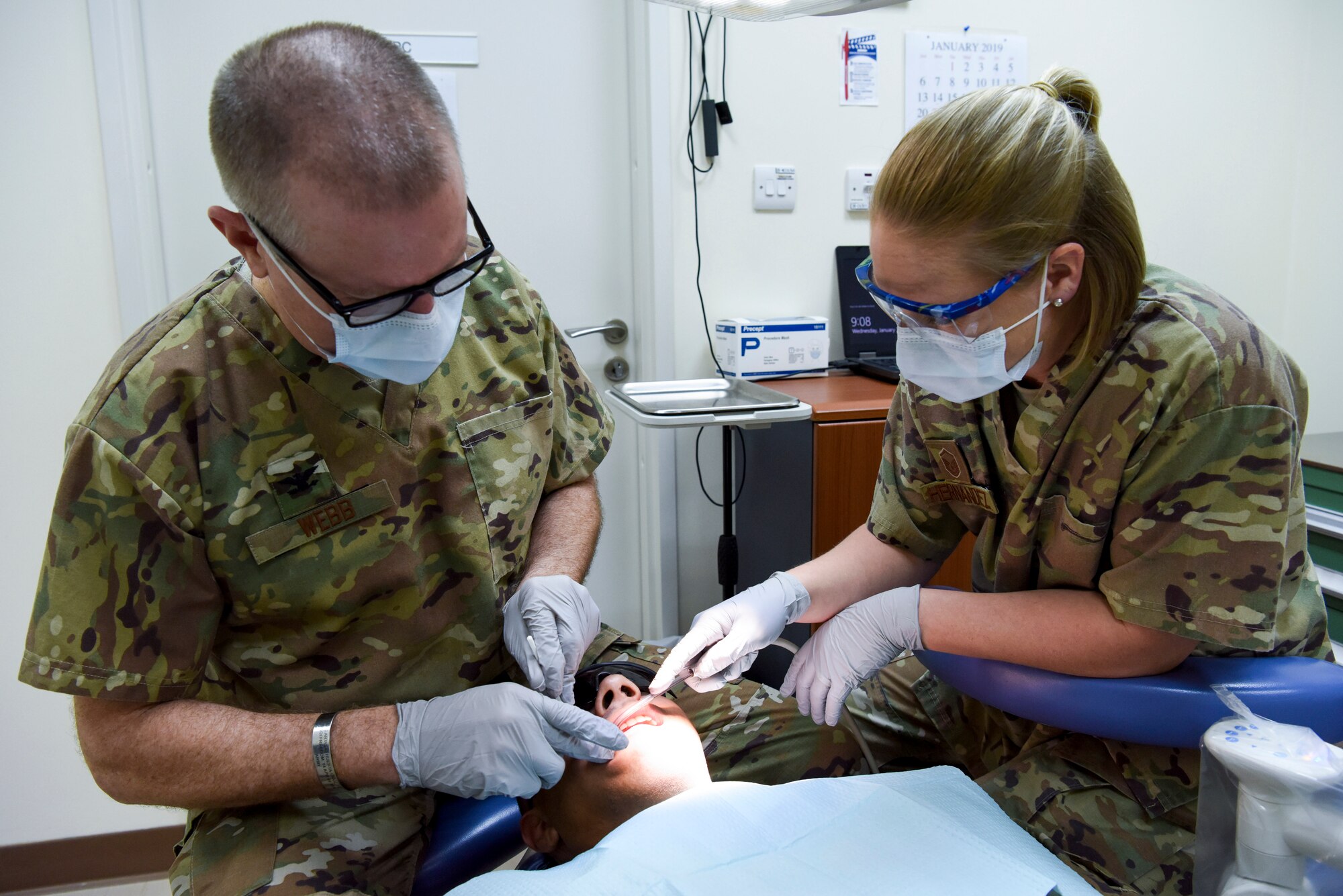 Col. Mike Webb, 380th EMDG comprehensive dentist, and Master Sgt. Audrey Hernandez, 380th EMDG dental technician, performs a dental exam, Jan. 30, 2019, at Al Dhafra Air Vase, United Arab Emirates.