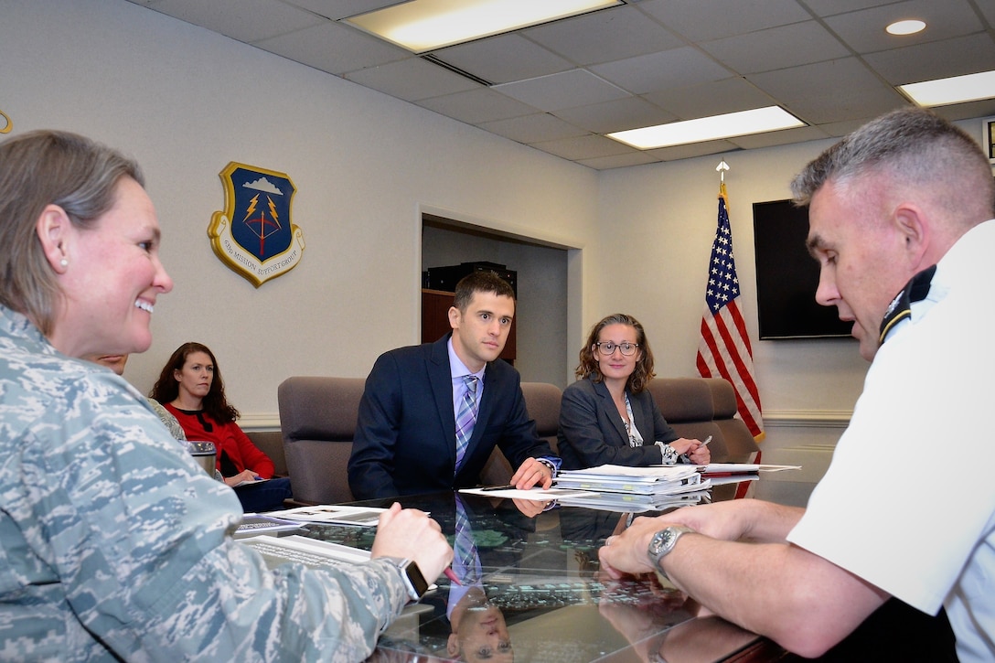 Woman in Air Force uniform on left and male in Army uniform on right talk to each other with a few people sitting at the table around them