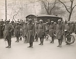 Soldiers of the 369th Infantry Regiment band stand at rest as they wait to march up Fifth Avenue in New York City on Feb. 17, 1919, during a parade held to welcome the New York National Guard unit home. More than 2,000 Soldiers took part in the parade up Fifth Avenue. The Soldiers marched seven miles from downtown Manhattan to Harlem. The band was led by noted musician Lt. James Reese " Jimmie" Europe, seen at center wearing glasses.