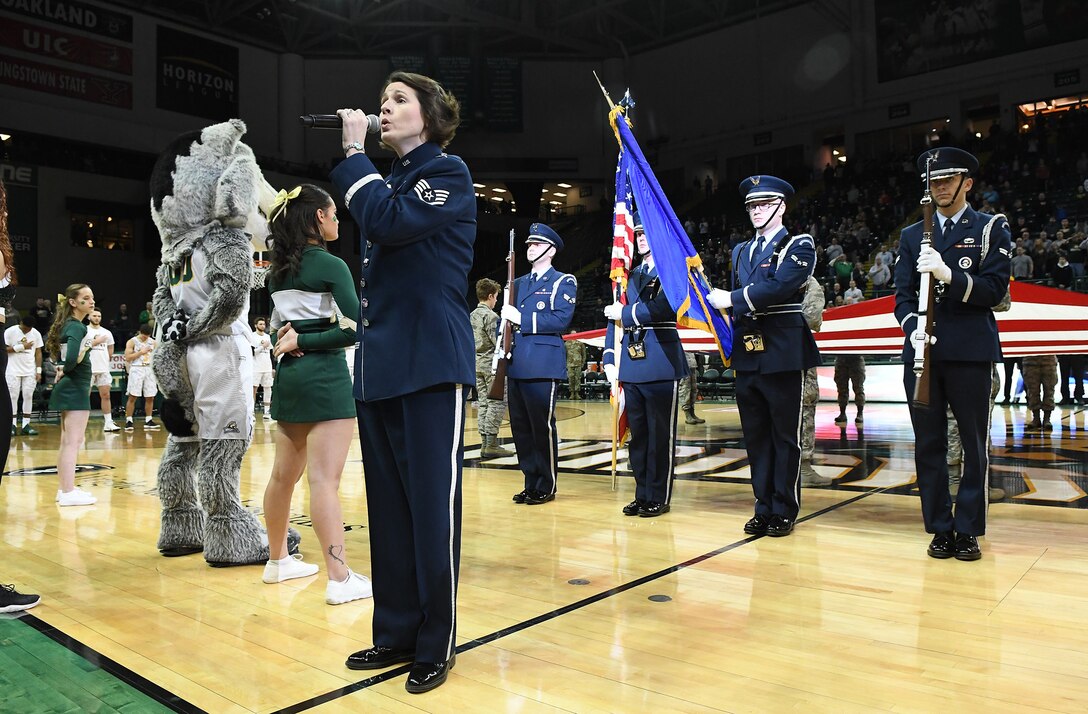 Staff Sgt. Joanne Griffin, U.S. Air Force Band of Flight vocalist, sings the national anthem as members of the Wright-Patterson Air Force Base Honor Guard present the colors at a military appreciation basketball game.