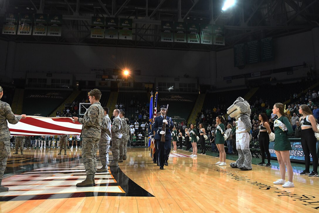 Members of the Wright-Patterson Air Force Base honor guard prepare to present the colors for the national anthem while 22 Airmen from the United States Air Force School of Aerospace Medicine present a large American flag at a Wright State men’s basketball game on Jan. 26, 2018, in the Erwin J. Nutter Center. (Courtesy photo).