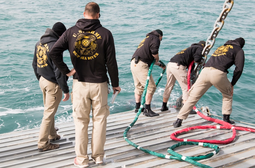 Soldiers assigned to the 86th Engineer Dive Detachment lower divers into the gulf using umbilical cords, which provides air and communications to divers, during dive supervisor training and qualification near Kuwait Naval Base, Kuwait, Jan. 22, 2019. The Soldiers operate as a team to ensure the divers accomplish their mission as safely as possible.