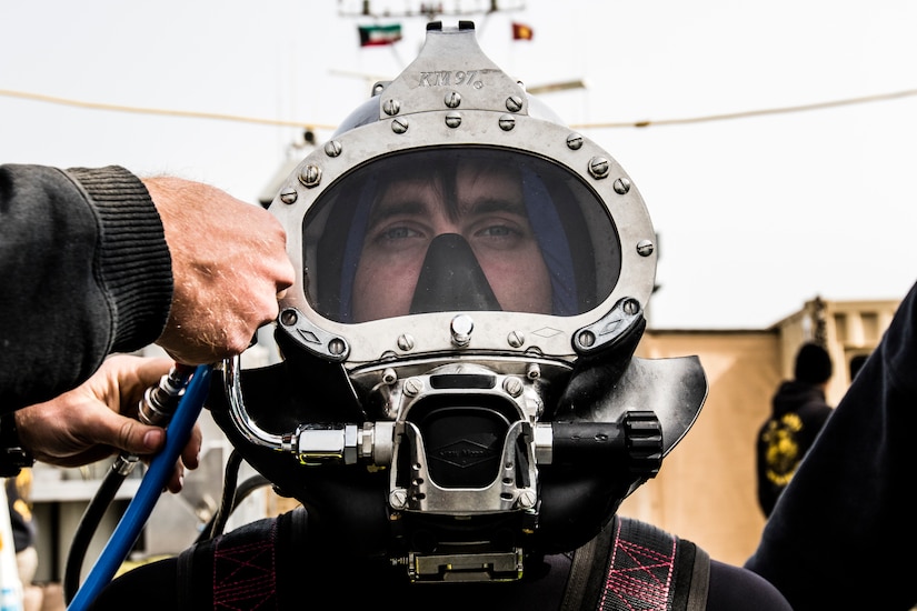Spc. Jordan P. Braiman, a second class diver assigned to the 86th Engineer Dive Detachment, waits as his equipment is checked before conducting a dive near Kuwait Naval Base, Kuwait, Jan. 22, 2019.  The 86th EDD conducted dive supervisor training and qualification to increase the number of Soldiers qualified to act as dive supervisors as well as to increase their units overall readiness.