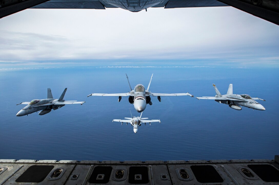 Four aircraft fly in formation behind another.