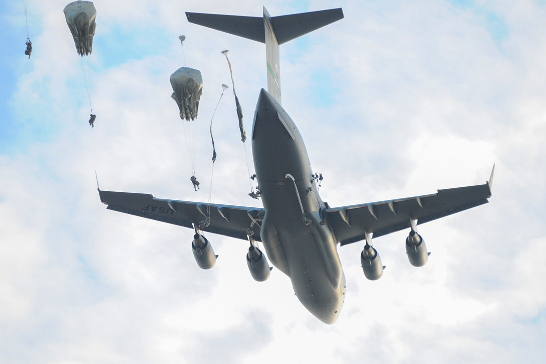 Paratroopers jump from a plane.