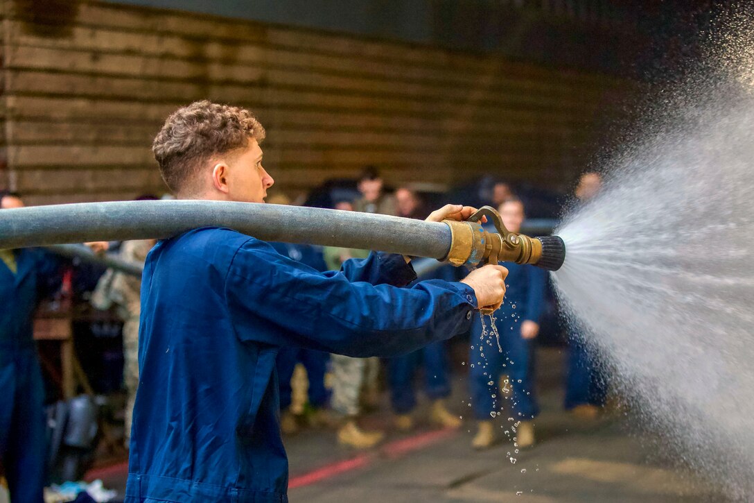 A Marine sprays a hose.