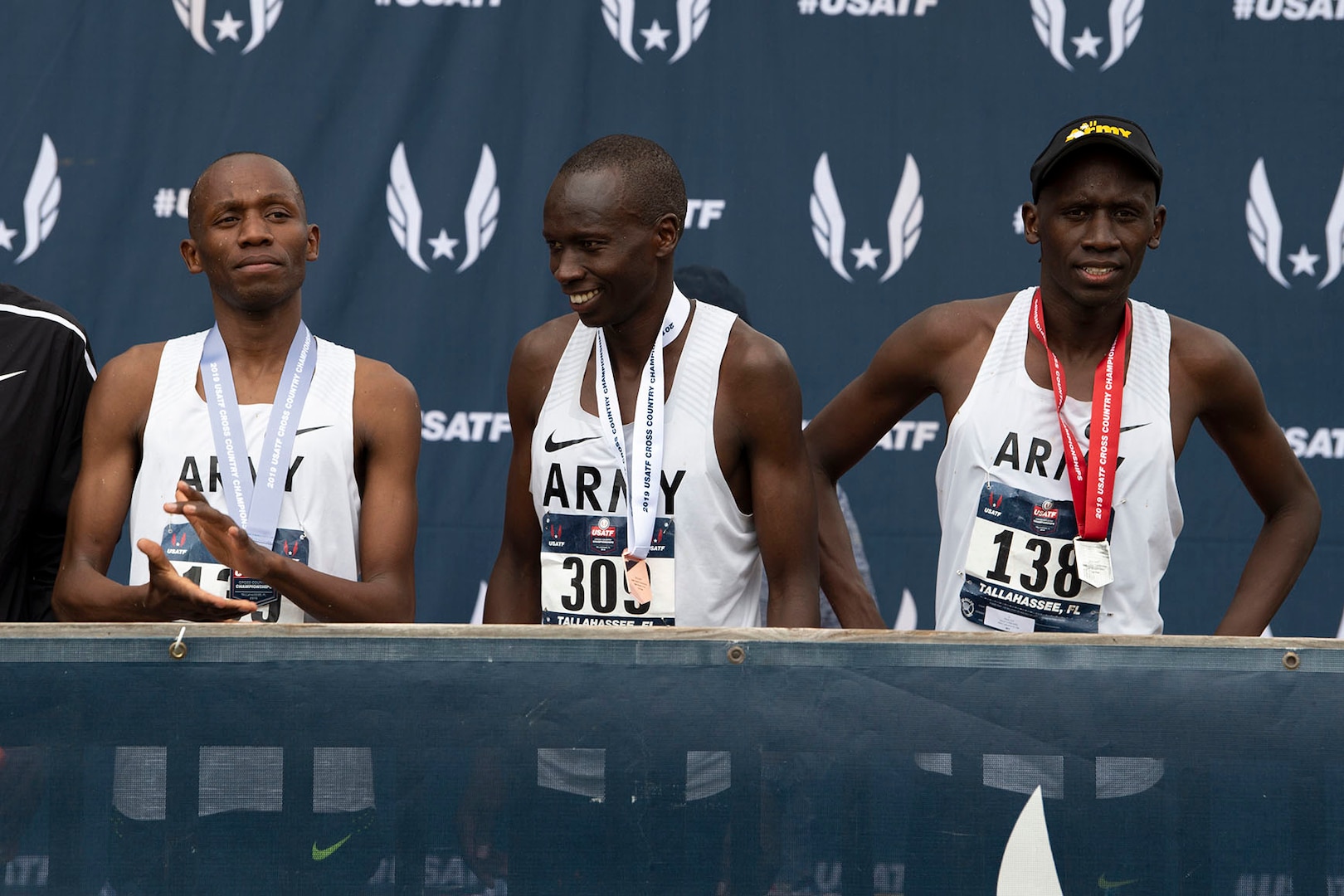 From left, Army Sgt. Hillary Bor, Army Sgt. Leonard Korir, and Army Sgt. Emmanuel Bor stand on an awards stage with their medals after placing the 2nd, 3rd, and 4th in the USA Track and Field Cross Country Championship