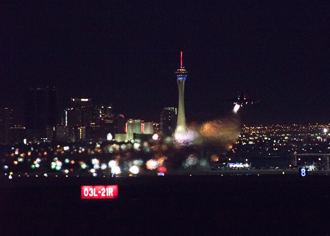 An F-16 Fighting Falcon fighter jet takes off with the city of Las Vegas, Nevada, in the background at night.
