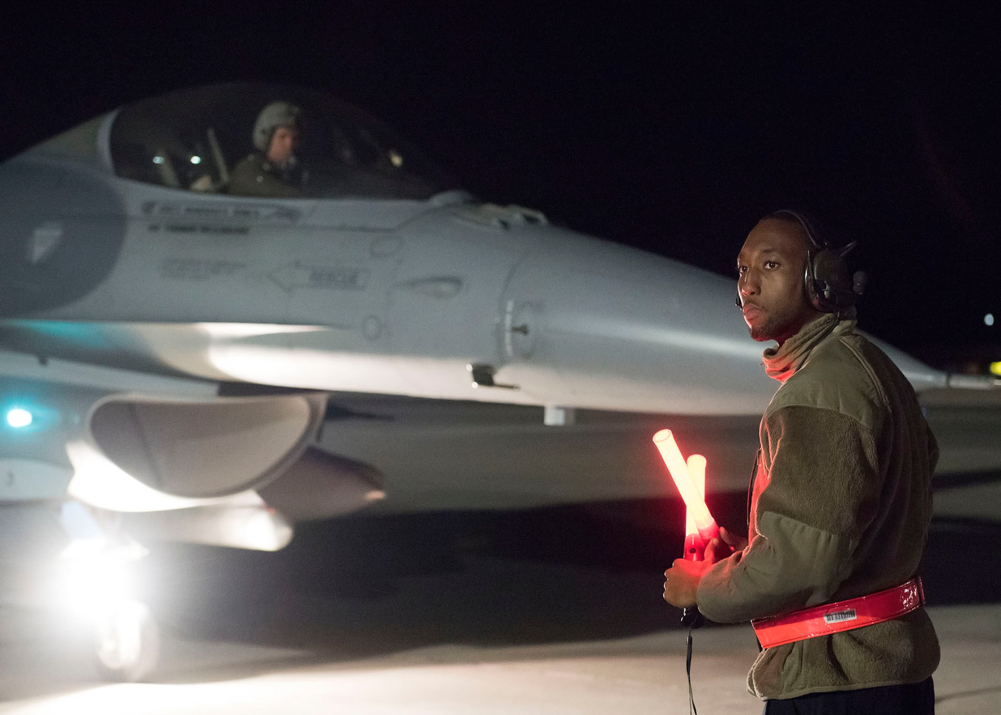 An Airman signals a pilot sitting in a F-16 Fighting Falcon fighter jet.