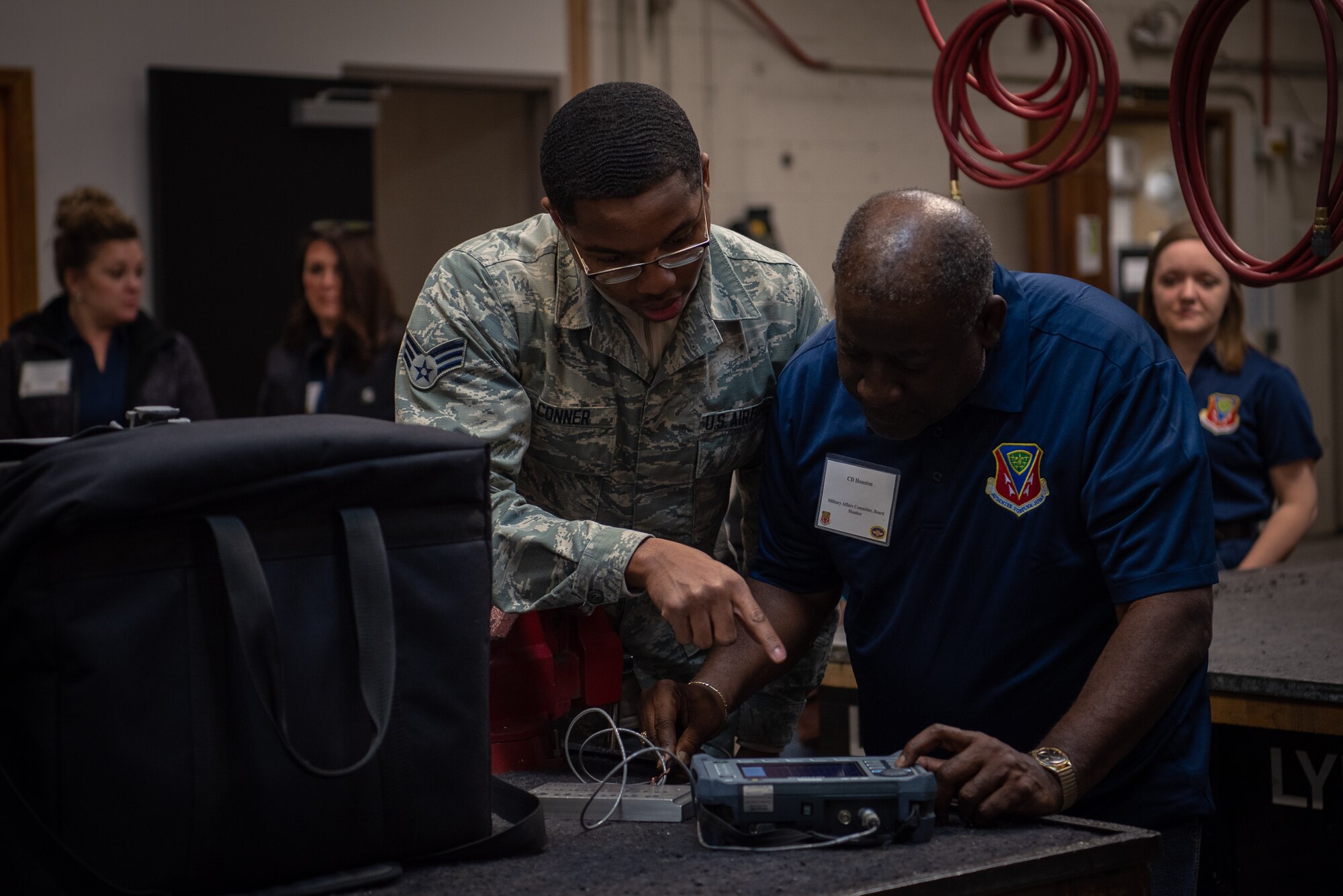 Senior Airman Armond Conner, 56th Equipment Maintenance Squadron nondestructive inspection journeyman, teaches C.D. Houston, Mountain Home Military Affairs Committee board member, how to detect cracks in a metal plate, Jan. 31, 2019 at Luke Air Force Base, Ariz.