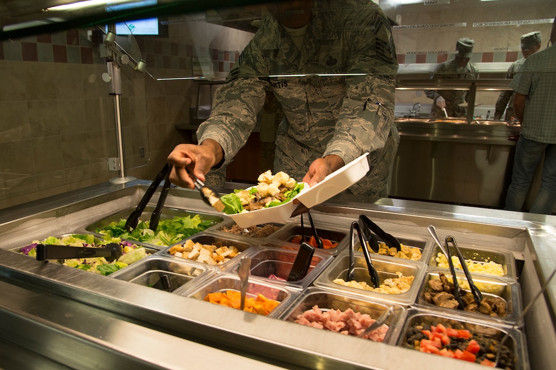 A service member uses a salad bar.