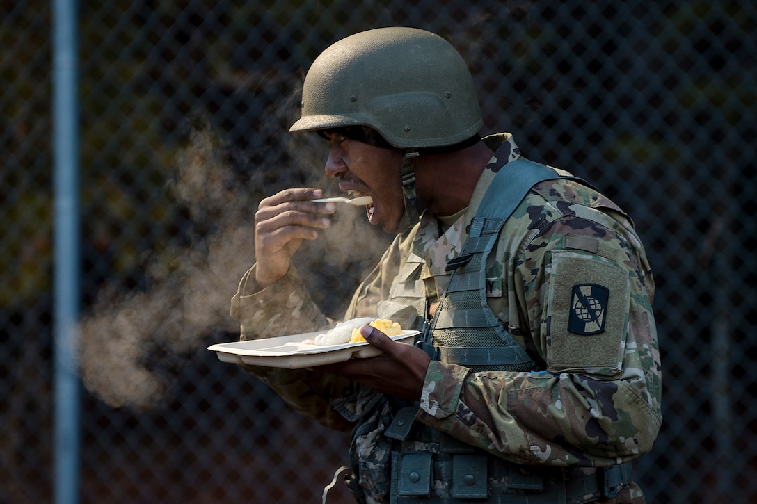 A soldier eats outdoors in the cold.