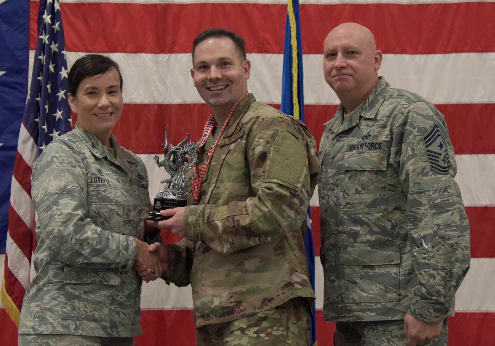 U.S. Air Force Col. Debra Lovette, 81st Training Wing commander, and Chief Master Sgt. David Pizzuto, 81st TRW command chief, present Tech. Sgt. Zachary Bosch, 334th Training Squadron instructor, with the NCO of the Year award during the 81st Training Wing's 2018 Annual Awards Ceremony inside a hangar at Keesler Air Force Base, Mississippi, Feb. 1, 2019. During the ceremony, base leadership recognized outstanding Airmen and civilians from across the installation for their accomplishments throughout 2018. (U.S. Air Force photo by Kemberly Groue)