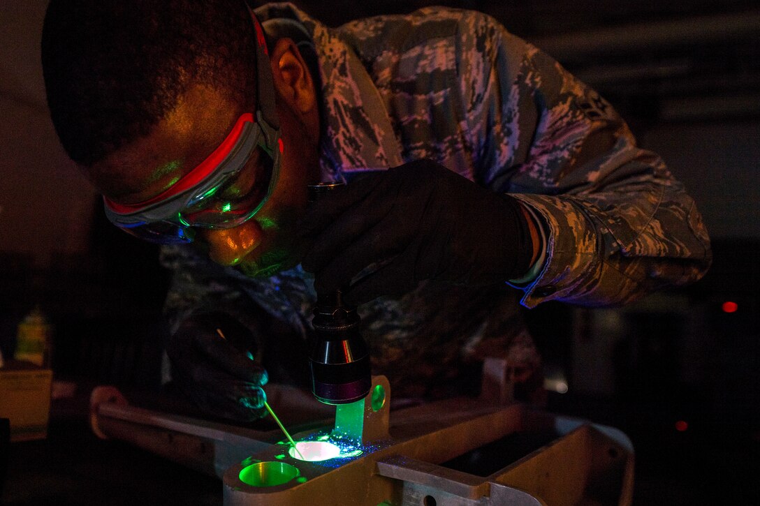 An airman scans airplane parts with a blacklight.