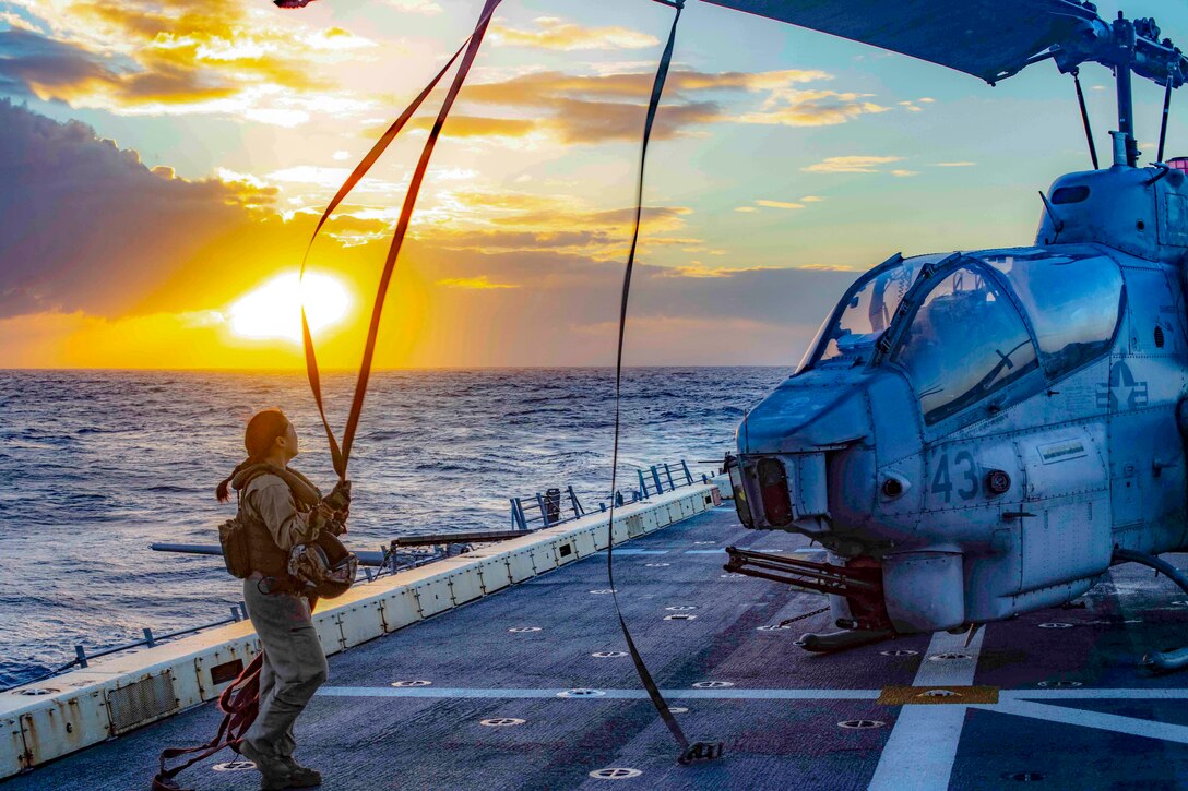 A Marine unties the rotors of a helicopter.