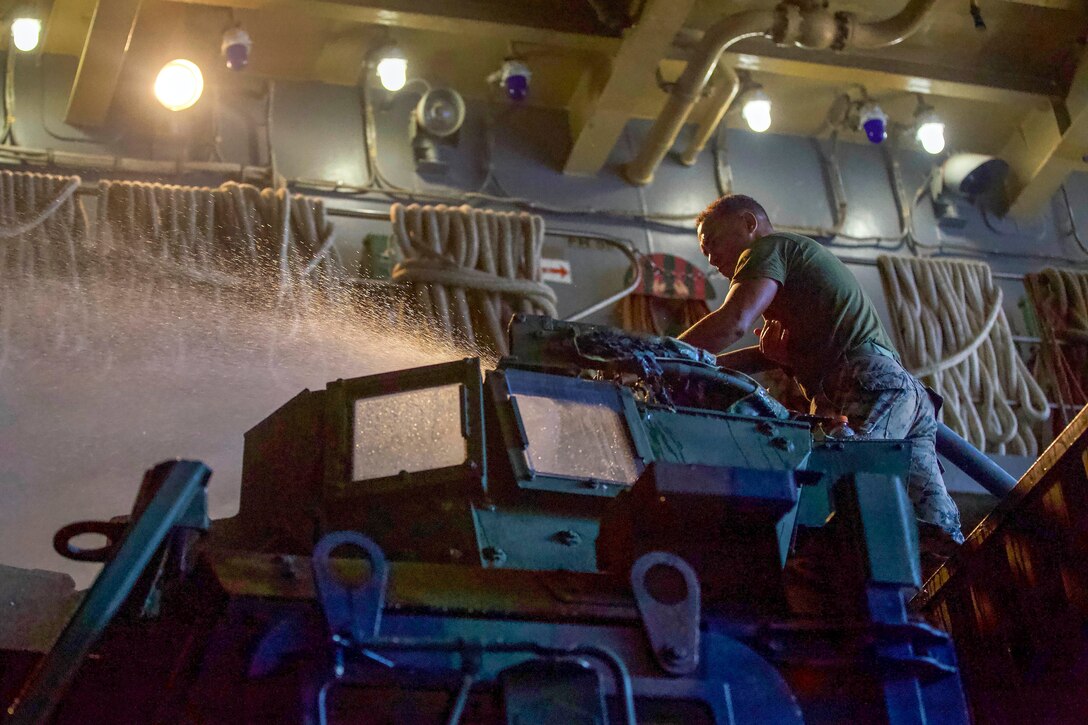 A Marine washes a vehicle down.