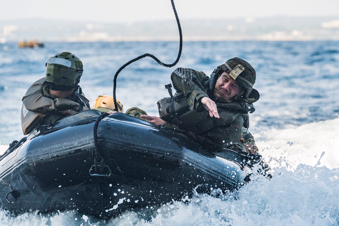 A Marine throws a rope from a rubber boat.