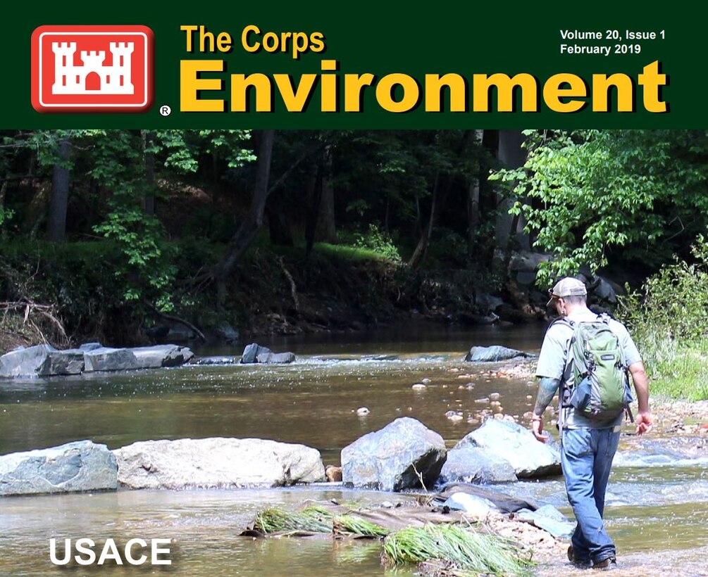 A man walks through a creek bed.