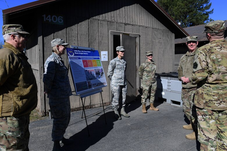 Men and women stand in an oval and talk.