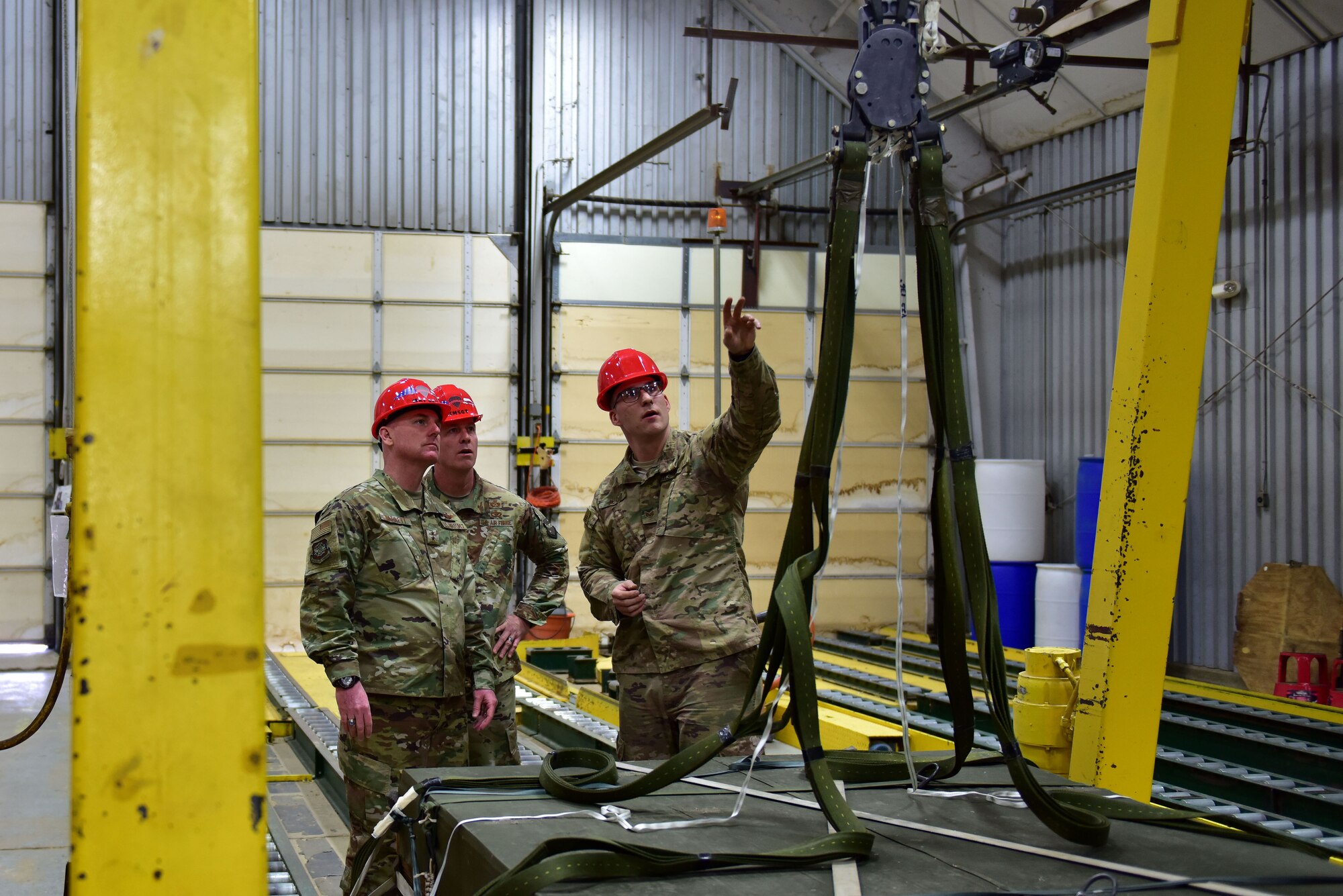 Men stand in front of a hoist and ropes.