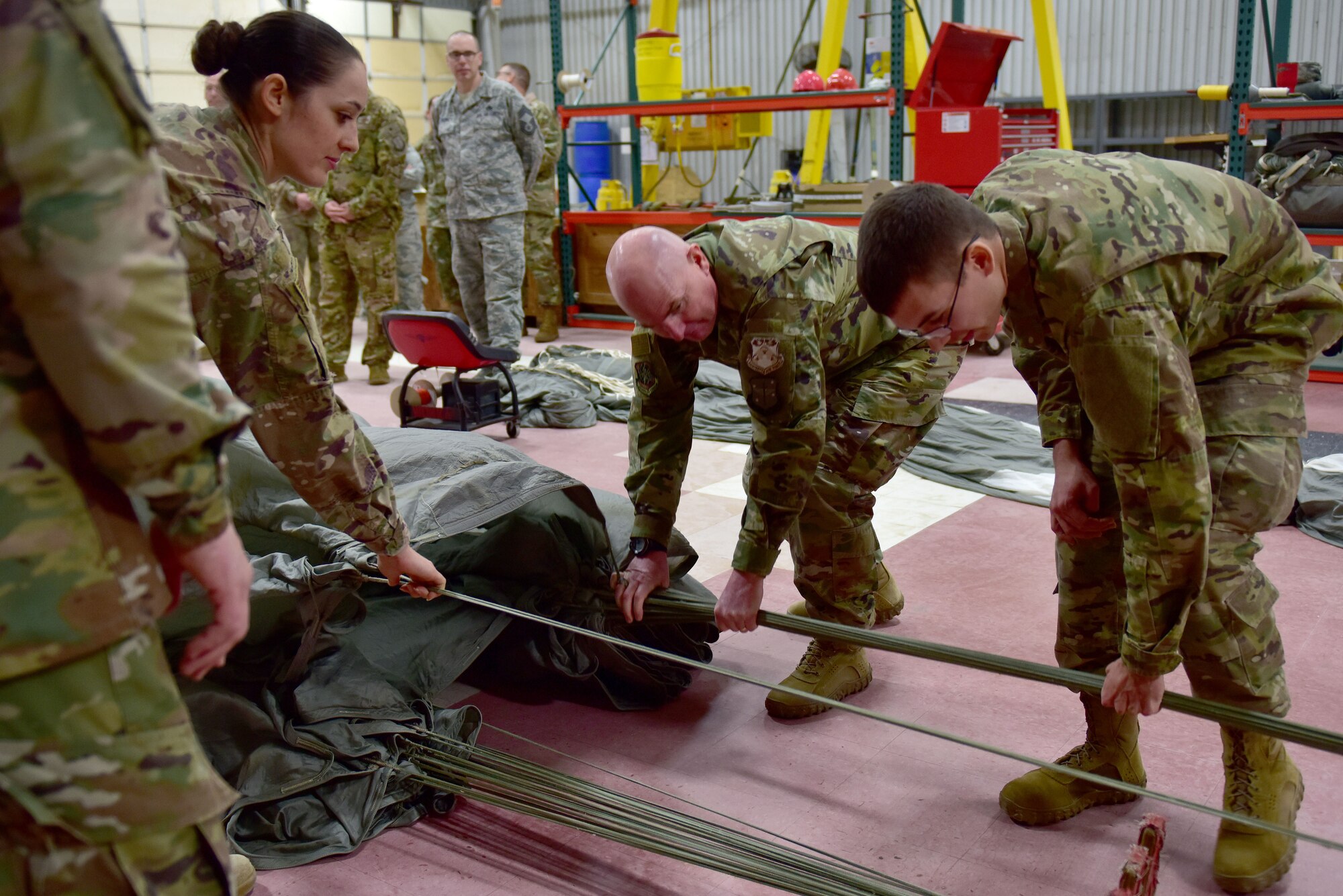 Men and women pull ropes on a parachute.