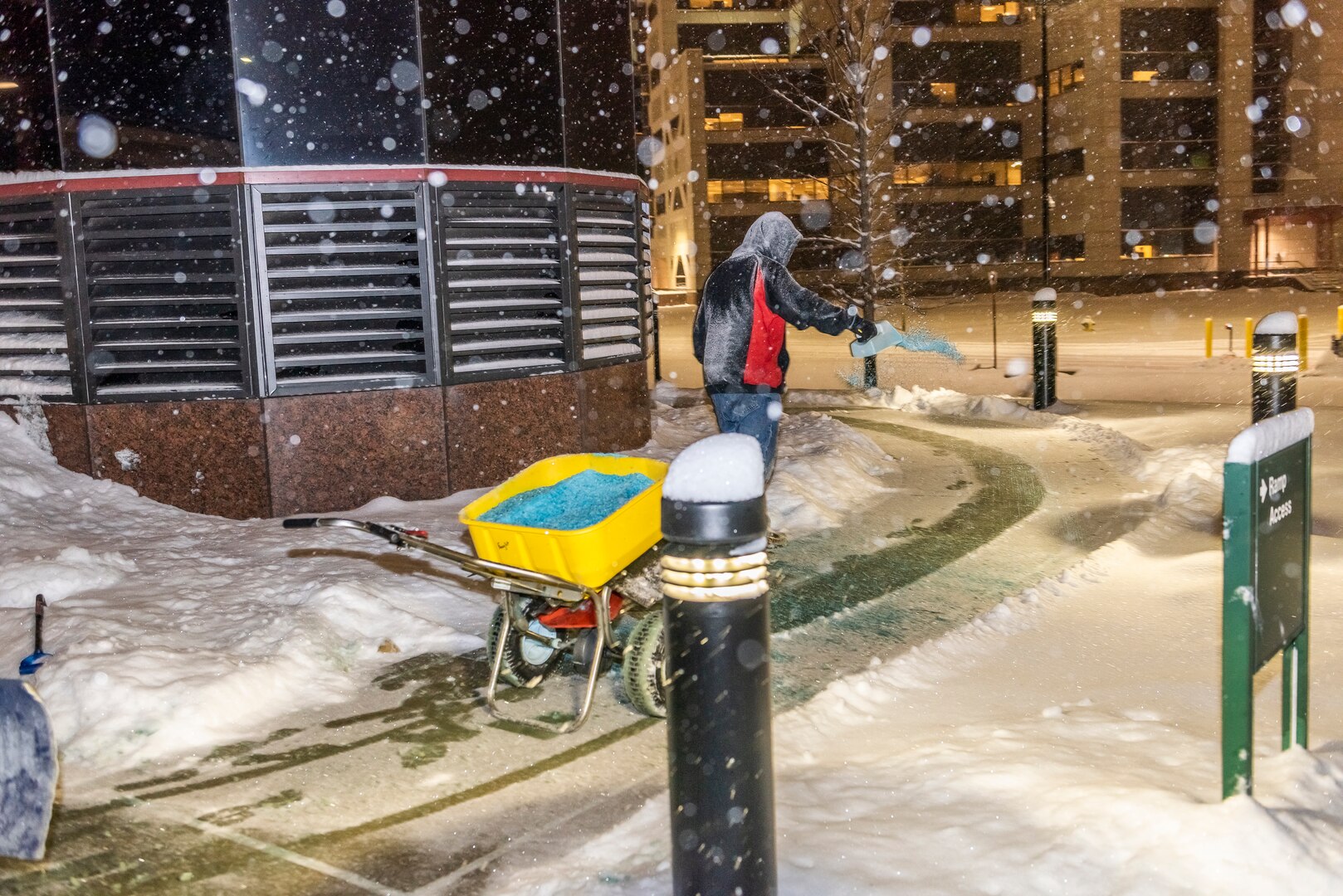 Guy spreading salt on sidewalks while it's snowing