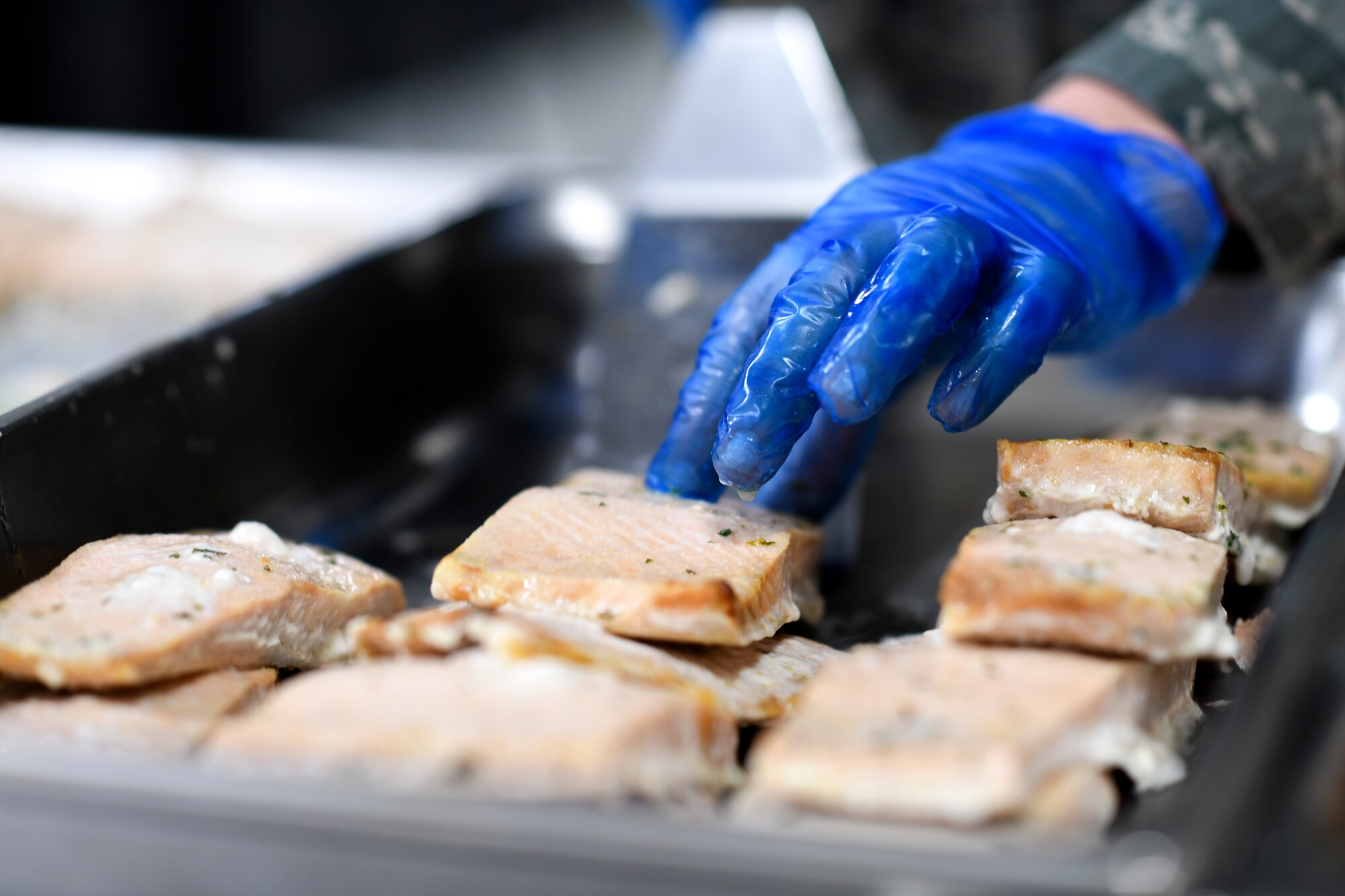 A chef assigned to the 48th Force Support Squadron prepares a serving container full of fish for dinner at the Knight’s Table dining facility on Royal Air Force Lakenheath, England, Jan. 31, 2019. Around 180 man-hours are accumulated to serve the hundreds of customers the facility supports within a single day. (U.S. Air Force photo by Senior Airman Malcolm Mayfield)