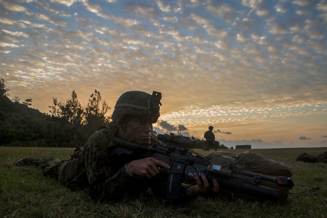 A Marine lies on a beach holding a machine gun during a training exercise.