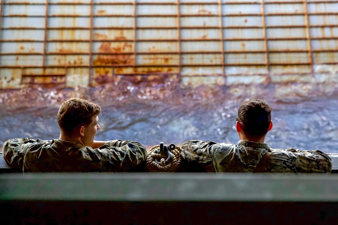 Two Marines peek their heads out of a landing craft.