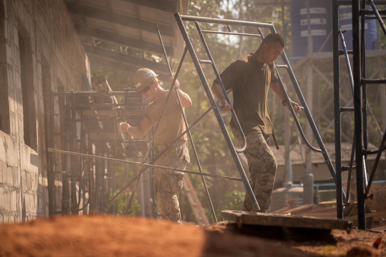 Two men carrying scaffolding