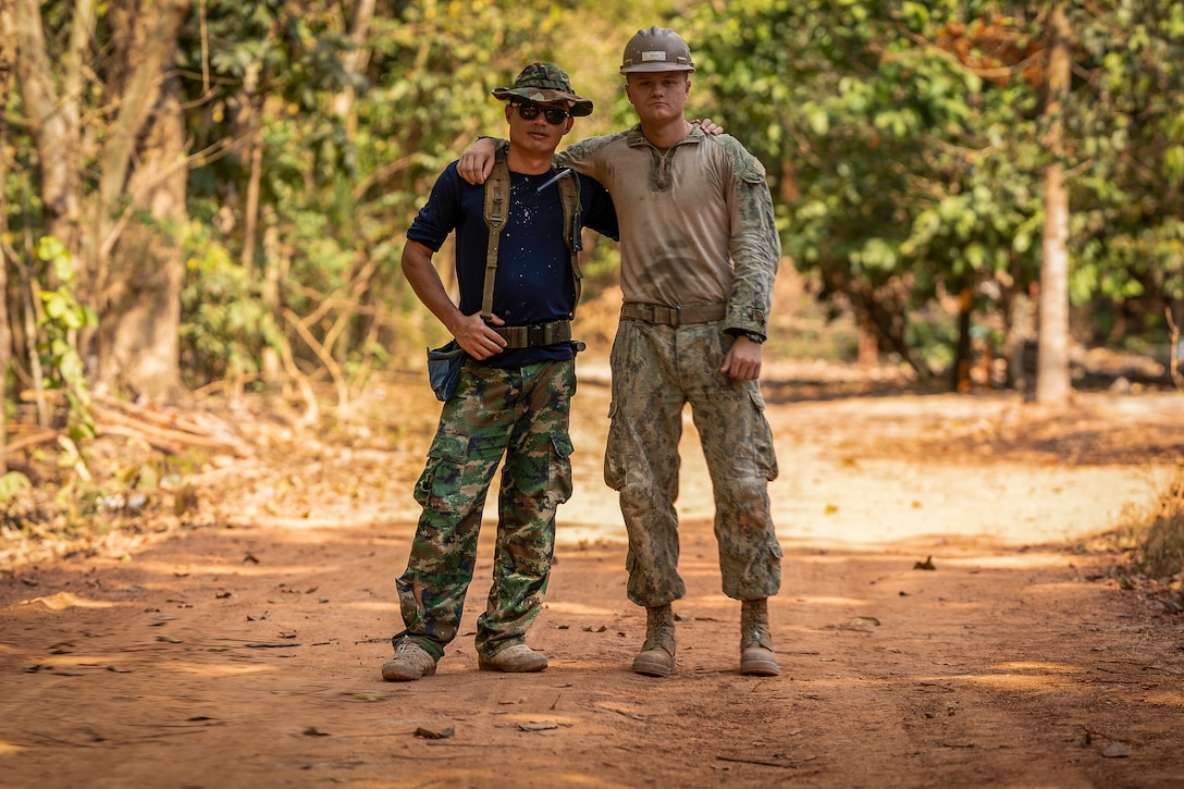 Two men standing together in a jungle path.