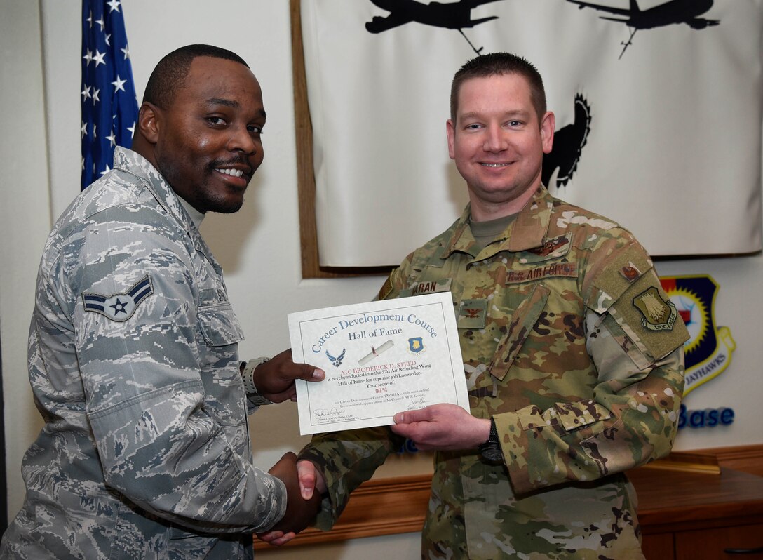 Senior Airman William Merth, 22nd Aircraft Maintenance Squadron integrated flight control system apprentice, left, is recognized by Col. Mark Baran, 22nd Air Refueling Wing vice commander, for earning a score of 95 percent on his Career Development Course Feb. 5, 2019, at McConnell Air Force Base, Kan. CDCs help enlisted personnel complete the specialty knowledge portion of on-the-job training for their specific career fields.