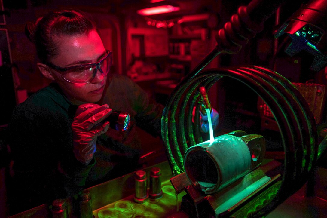A sailor uses a specialized device on a small aircraft piece.
