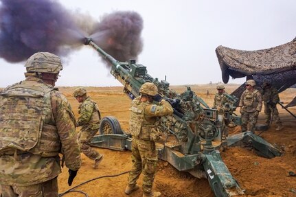 Soldiers fire a howitzer.