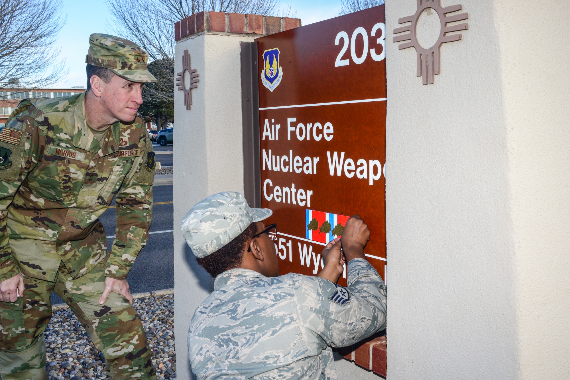 Air Force Nuclear Weapons Center Commander Maj. Gen. Shaun Morris and AFNWC’s Staff Sgt. Mychavia Harris,  the center’s most junior member in 2016, prepare to place a fourth oak leaf cluster on the center’s sign on Wyoming Blvd. here Feb. 1, 2019. The oak leaf cluster was the center’s fifth organizational excellence award since its inception in March of 2006. (U.S. Air Force photo by Jim Fisher)