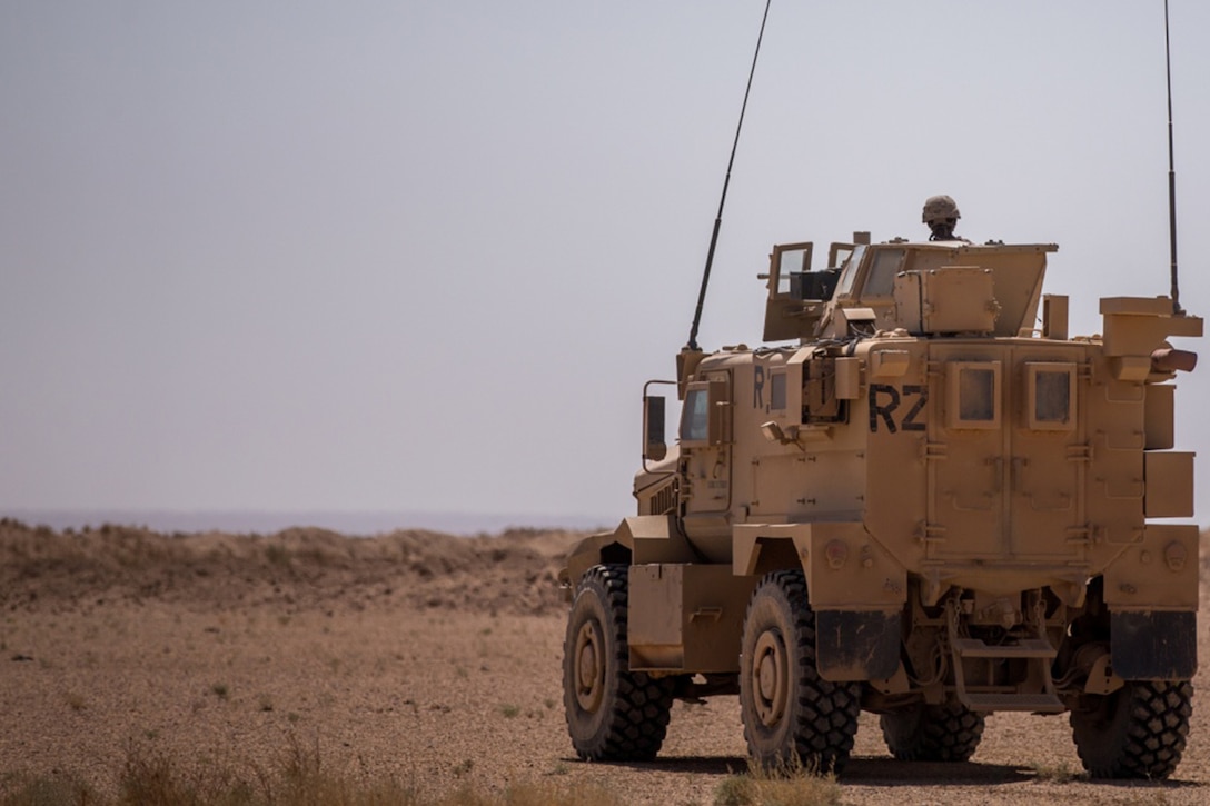Military vehicle moves through desert.
