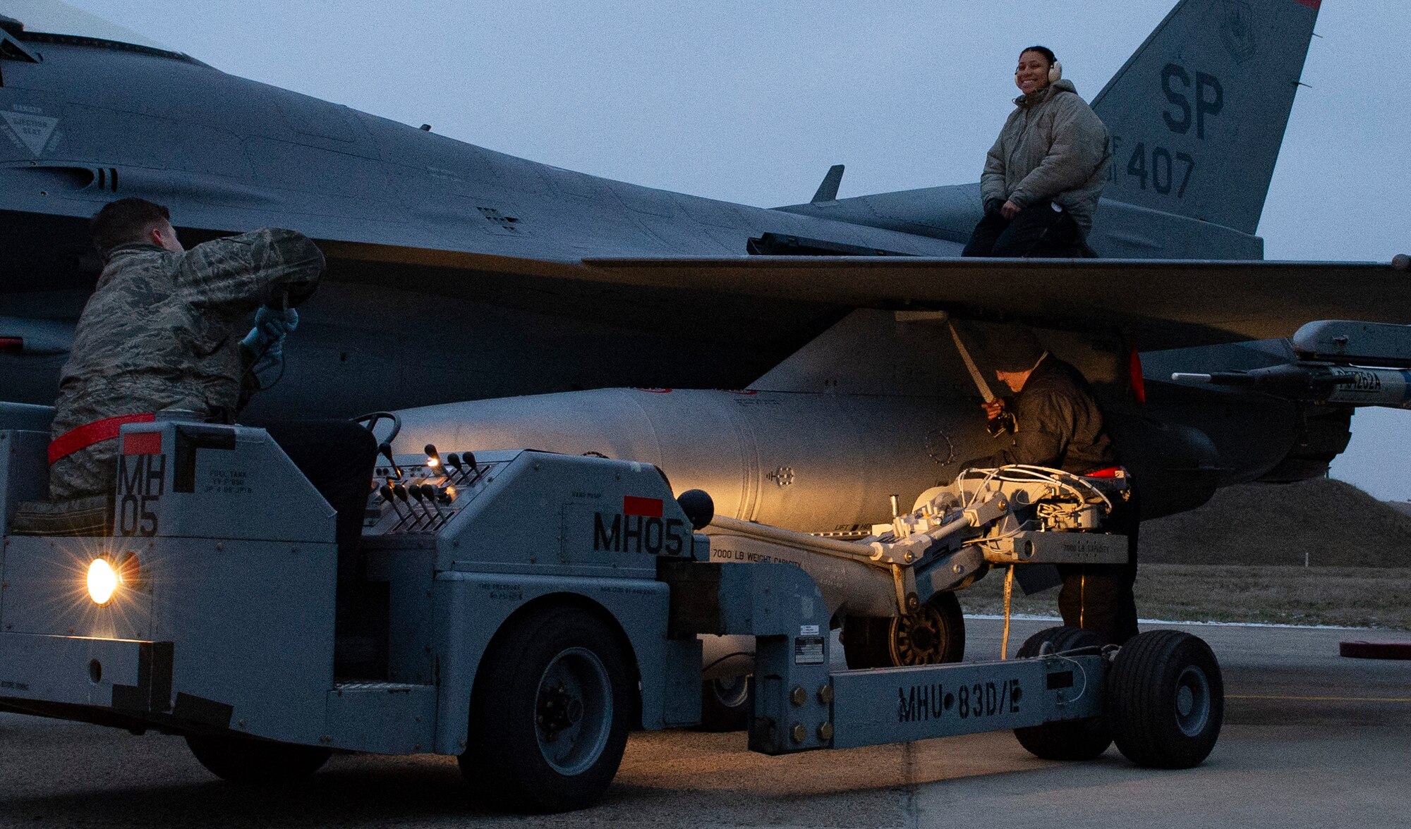 Load crews communicate through hand signals while loading pods, tanks, and missiles.