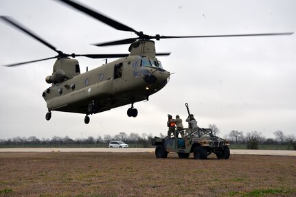 A Texas Army National Guard CH-47 Chinook approaches a Humvee as the ground crew prepares to hook connect the vehicle for airlifting during Operation Dust Storm at Martindale Army Air Field, Texas Feb. 1, 2019.