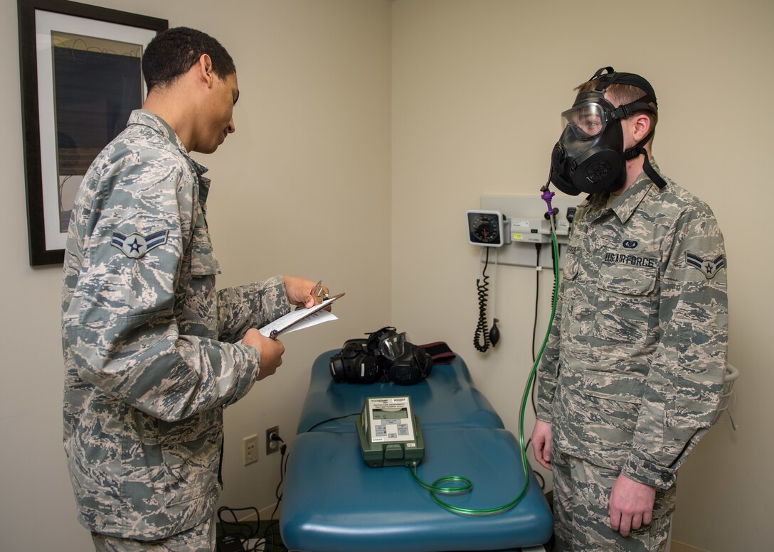 U.S. Air Force Airman 1st Class Cameron Rice, 633rd Aerospace Medicine Squadron bioenvironmental engineering technician, guides Airman 1st Class Evan Ferris, 633rd Air Base Wing Command Post emergency action controller, through the gas mask fit test at Joint Base Langley-Eustis, Virginia, Feb. 5, 2019.