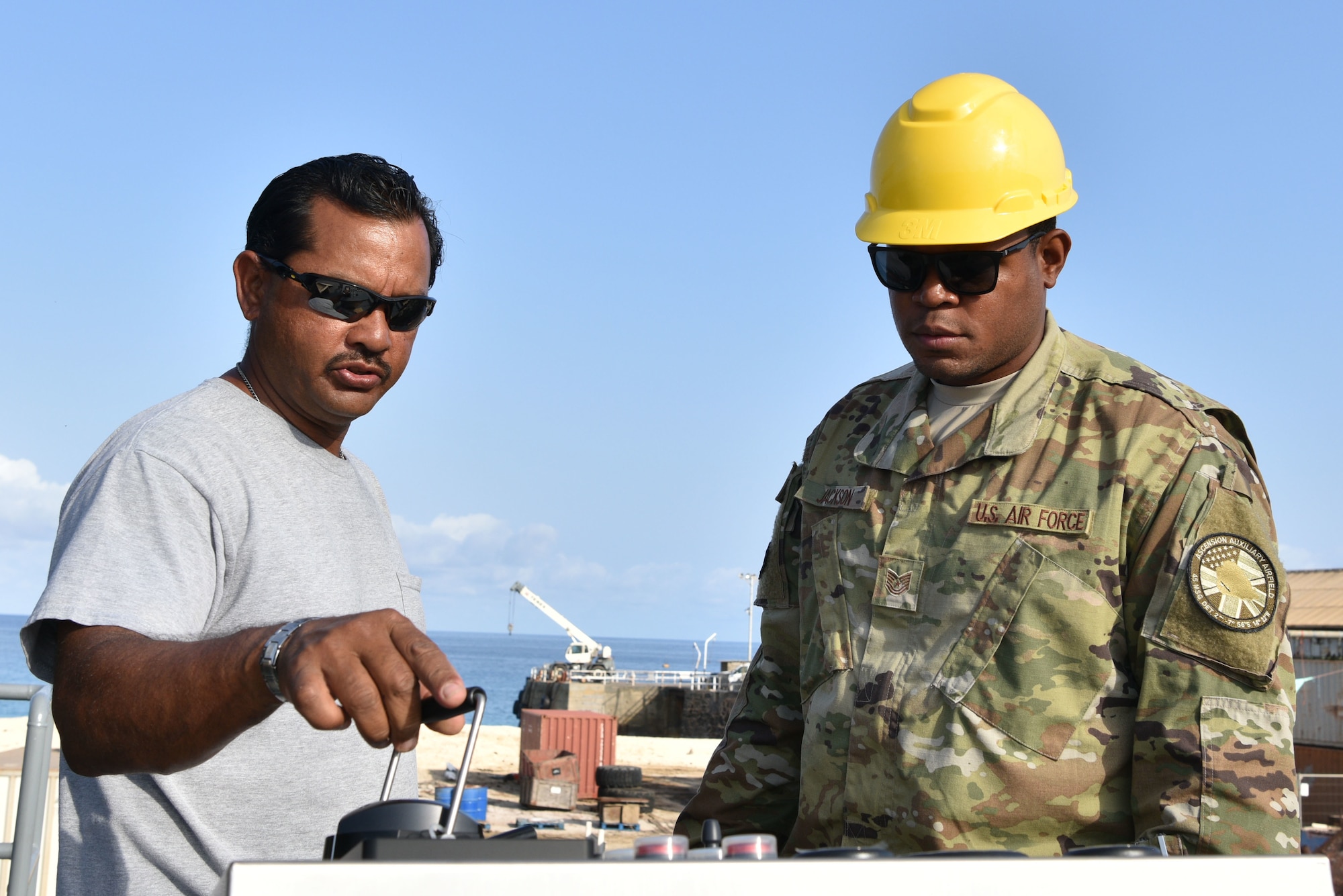 Tech. Sgt. Johntavion Jackson, 45th Civil Engineering Squadron contracting officer, looks over barge operating controls with an Ascension Island contractor, January 17, 2019 at Ascension Island Auxiliary Airfield. When Ascension receives supplies by ship, they can use barges to deliver supplies to the island. (U.S. Air Force photo by Airman 1st Class Dalton Williams)