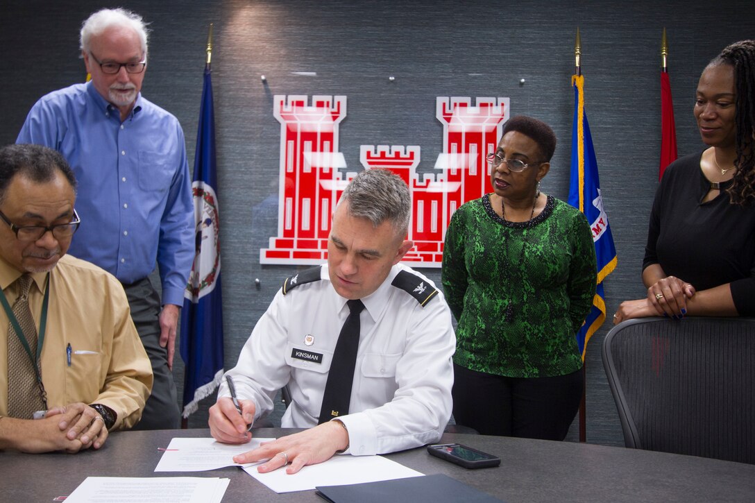 Norfolk District Commander, Col. Patrick Kinsman signs the Norfolk Harbor Navigation Improvements Design Agreement as District employees look on today at the District headquarters building.