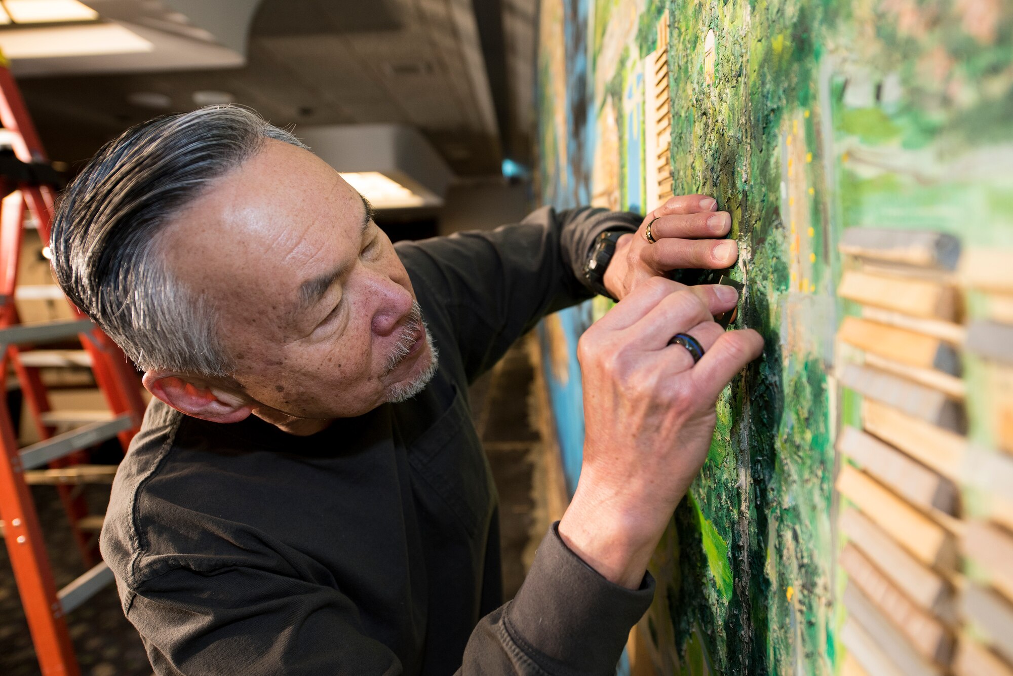 A volunteer from the Strategic Air Command Museum removes a 40-foot mural from the Global Lounge Jan. 29, 2019, at Offutt Air Force Base, Nebraska. The mural was installed in the, the, officer’s club in the 1960s. (U.S. Air Force photo by Delanie Stafford)